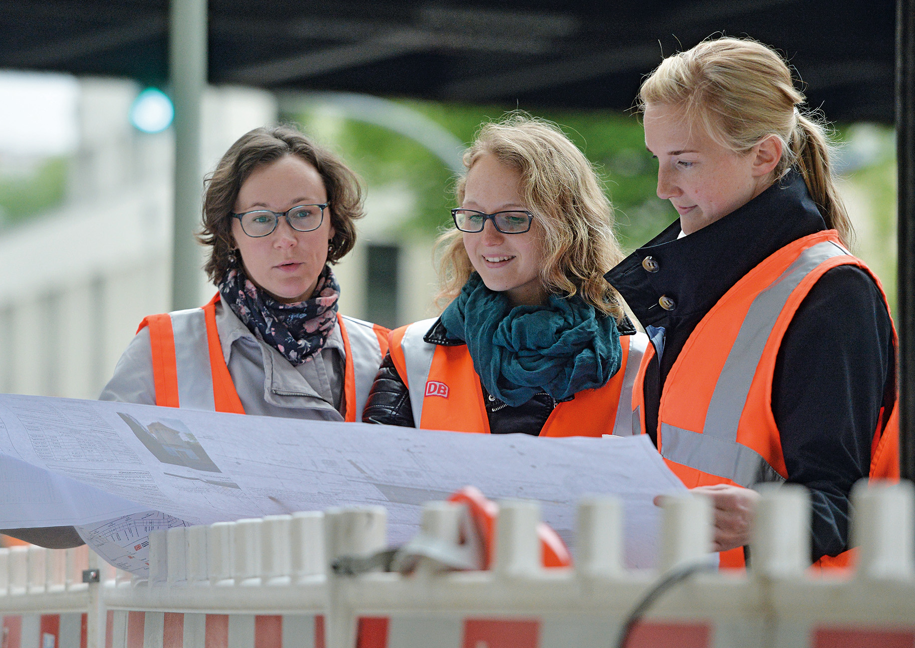Drei junge Bahningenieurinnen an einer Baustelle