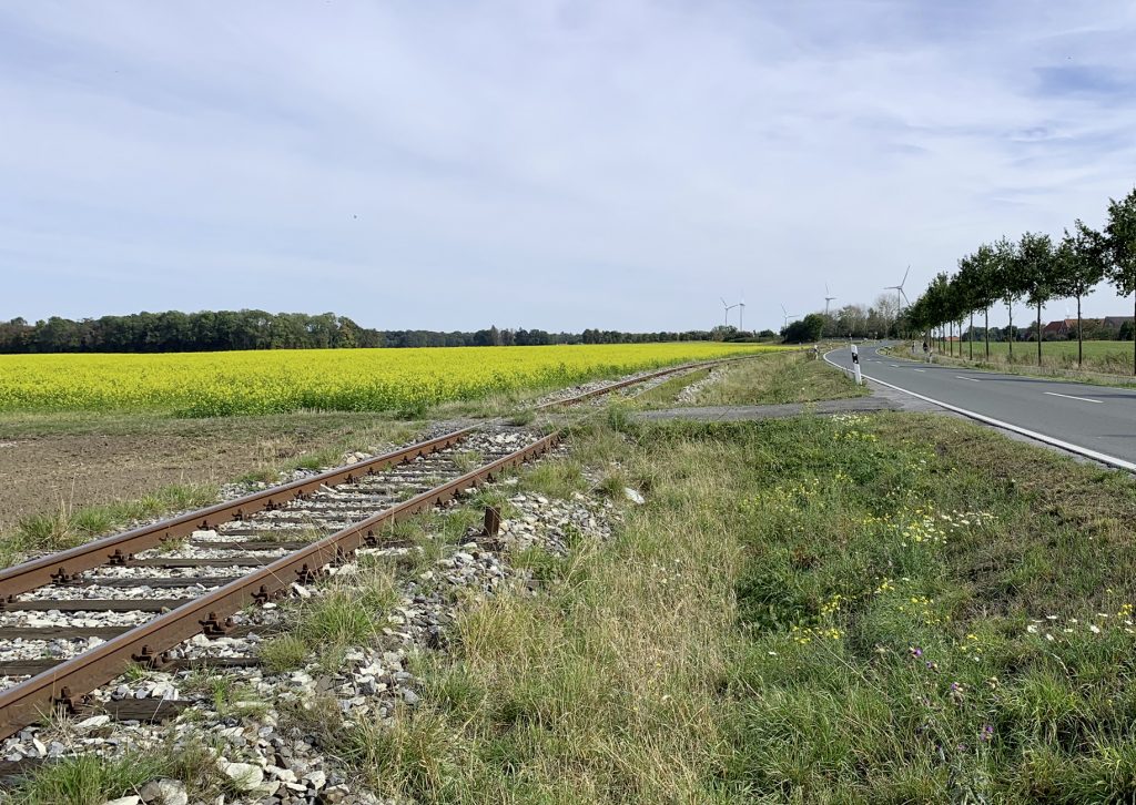 Landschaft mit Gleisen neben einer Landstraße