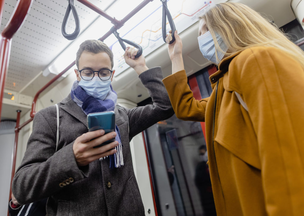 Fahrgäste in Nahverkehrszug mit Mund-Nase-Bedeckung