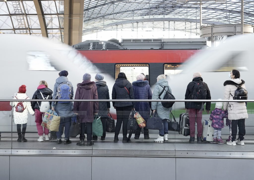 Eltern mit Kindern und Gepäck warten am Bahnsteig